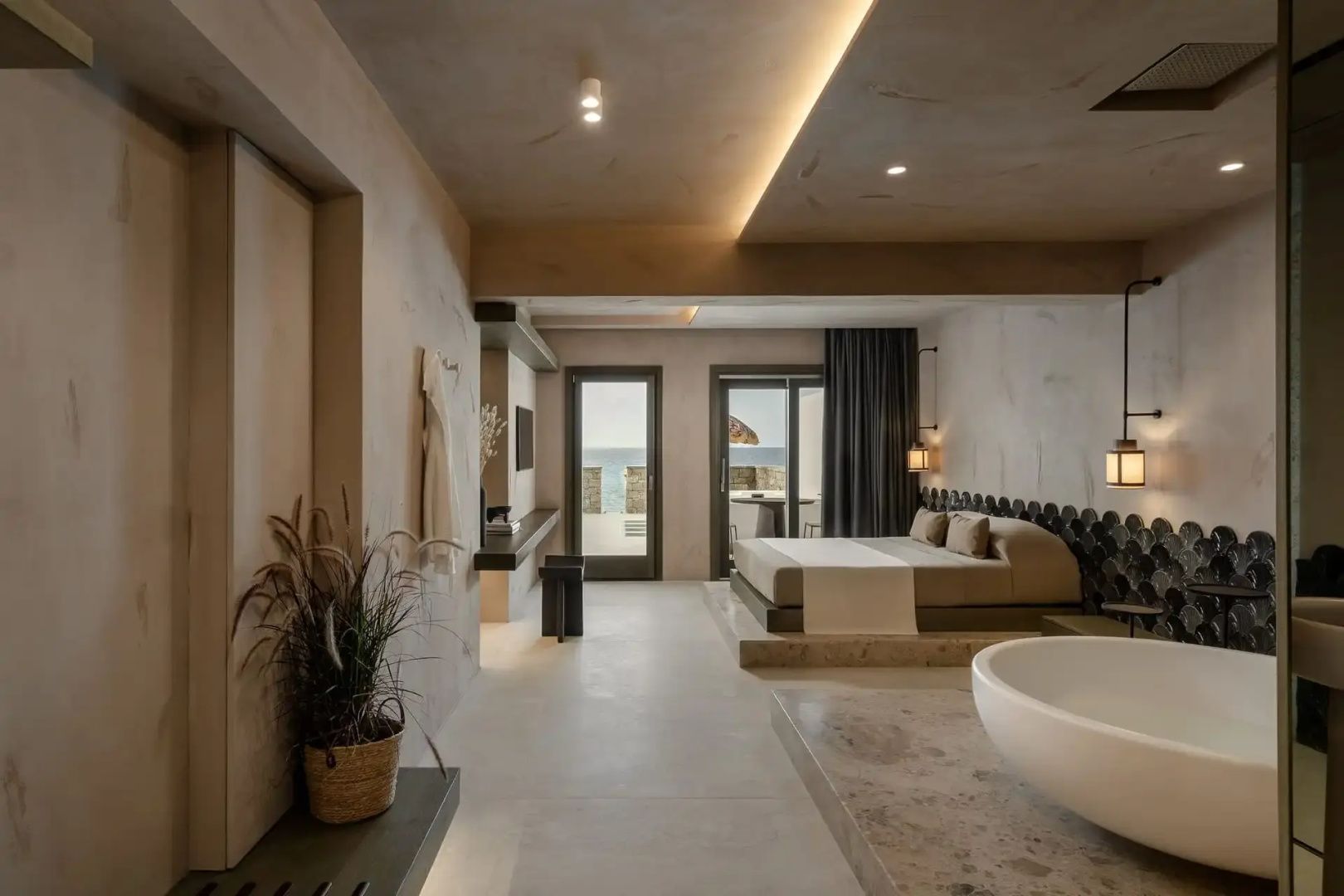 Geräumiges Hotelzimmer mit Doppelbett, frei stehender Badewanne und Balkonzugang.