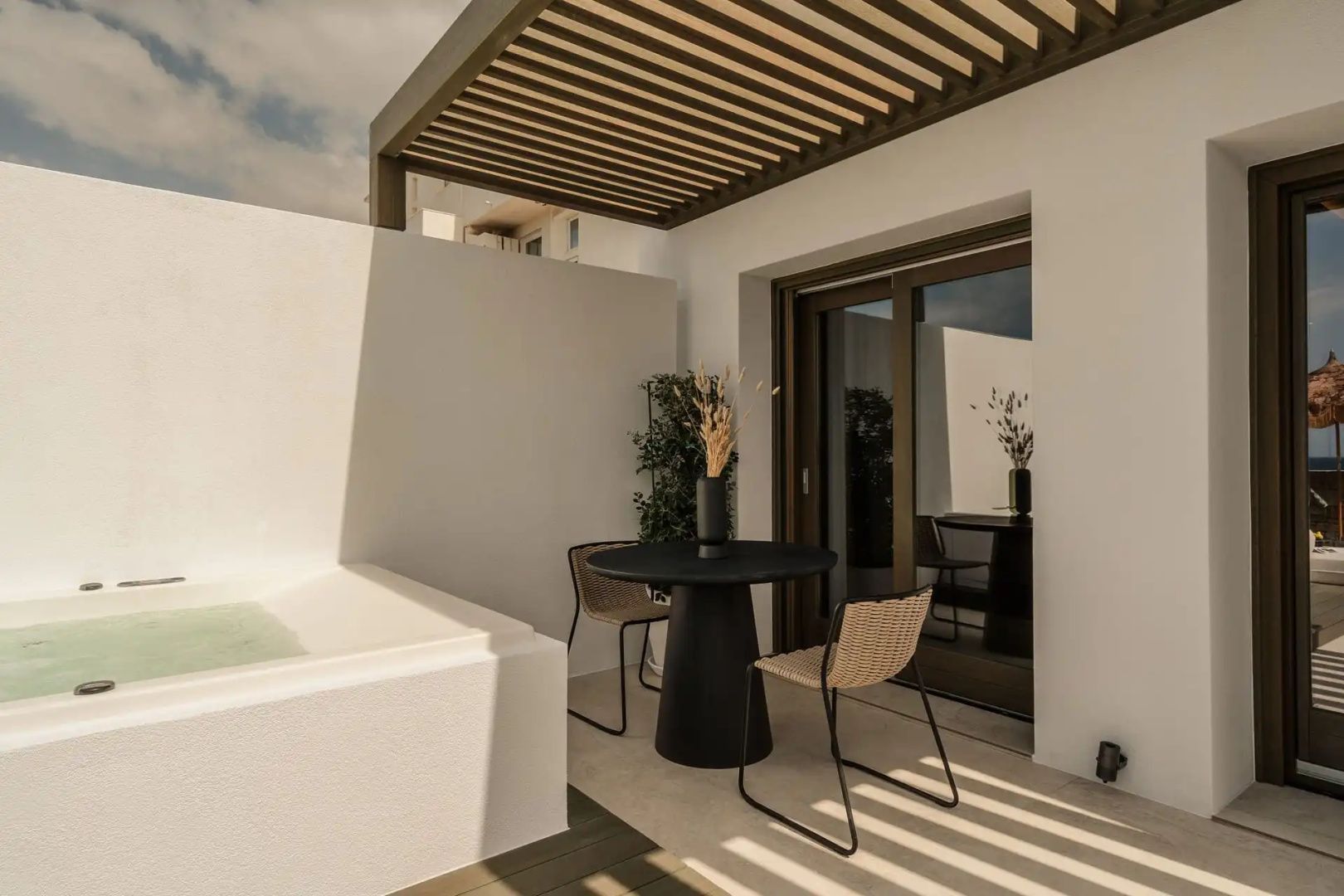 Überdachte Terrasse mit schwarzem Esstisch, zwei Stühlen und einer integrierten Whirlpool Wanne.