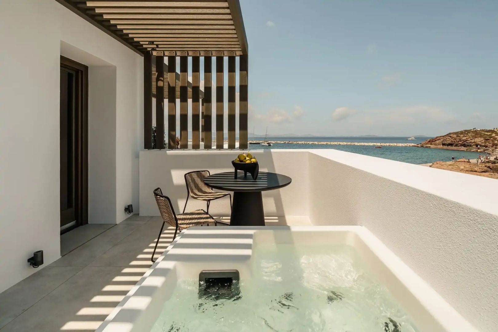 Überdachter Balkon mit kleinem Whirlpool, Sitzgruppe und Ausblick auf das Meer.