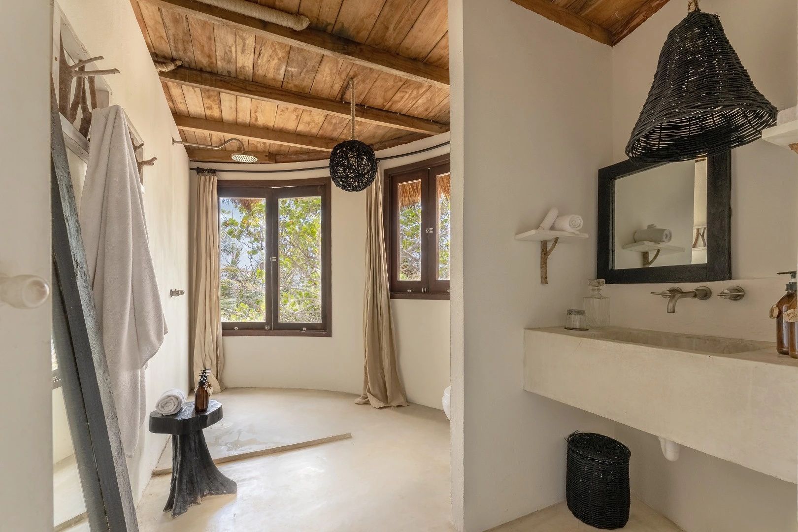 Badezimmer mit Holzdecke, Waschtisch, großer Dusche und Fenster ins Grüne.