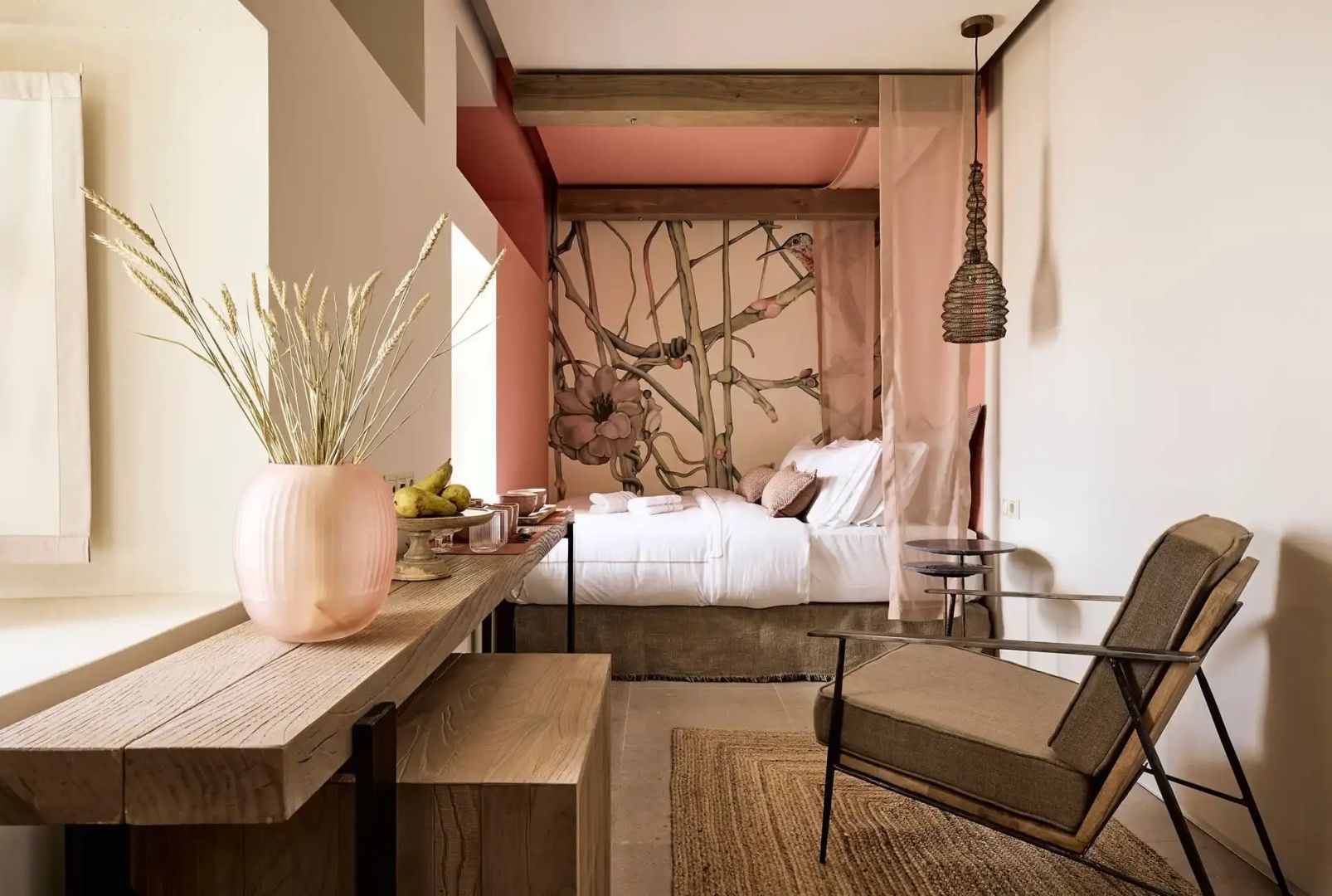 Eingerichtetes Schlafzimmer mit Bett, Holzmöbeln und pflanzlichem Wandmotiv.