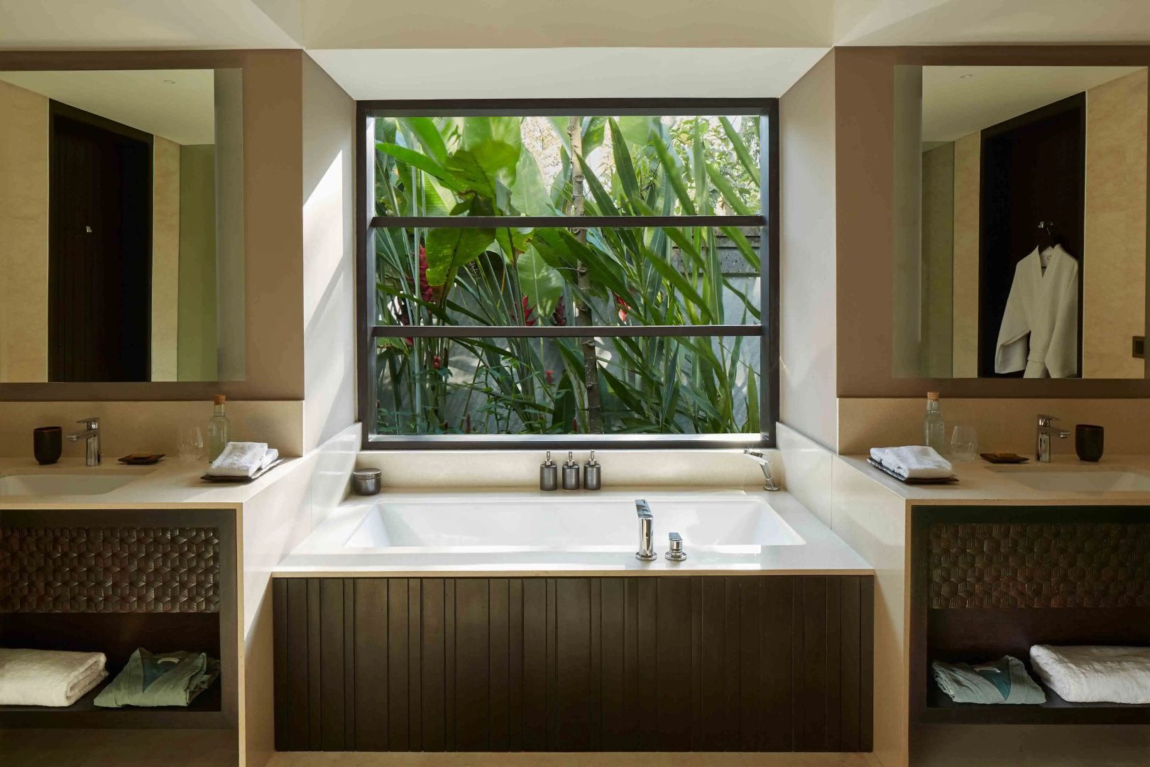 Eingebautes Badewanne unter einem großen Fenster mit Blick auf tropisches Grün.