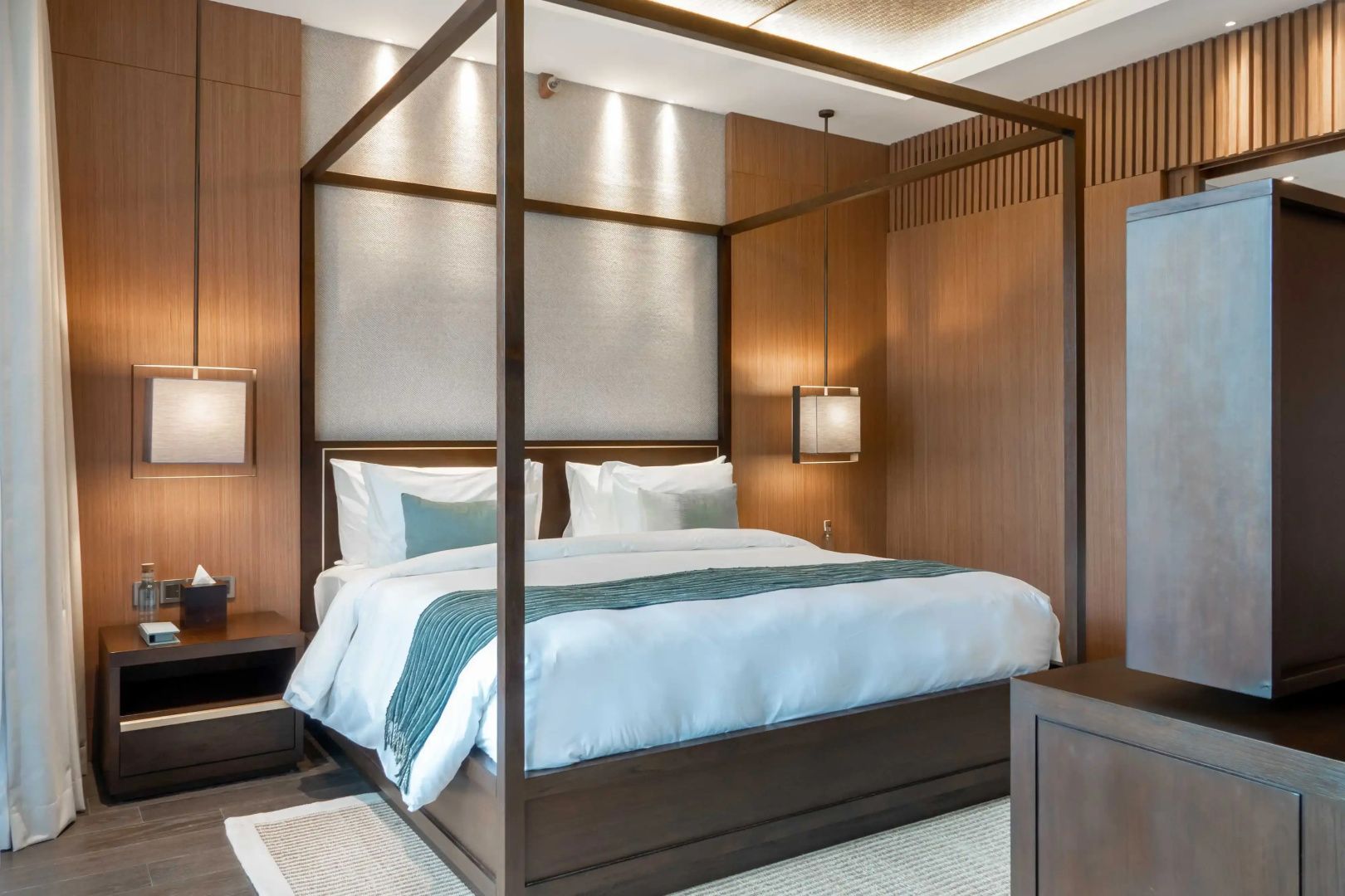 Großes Himmelbett aus dunklem Holz mit weißer Bettwäsche in einem Schlafzimmer.