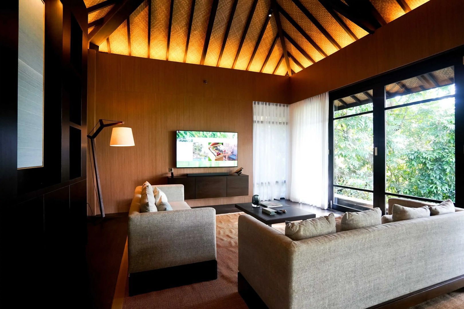 Wohnbereich mit zwei hellen Sofas, Flachbildfernseher und einer hohen Holzdecke.