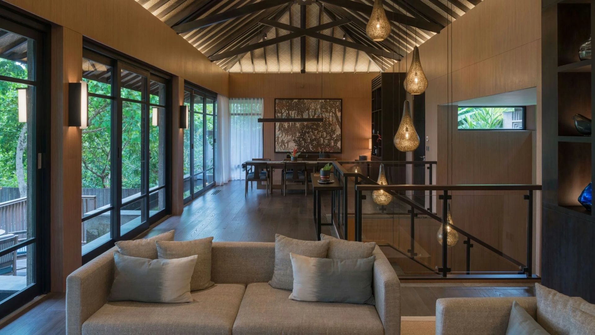 Großer Wohnbereich einer Villa mit Sofa, Esstisch und beleuchteter Holzdecke.
