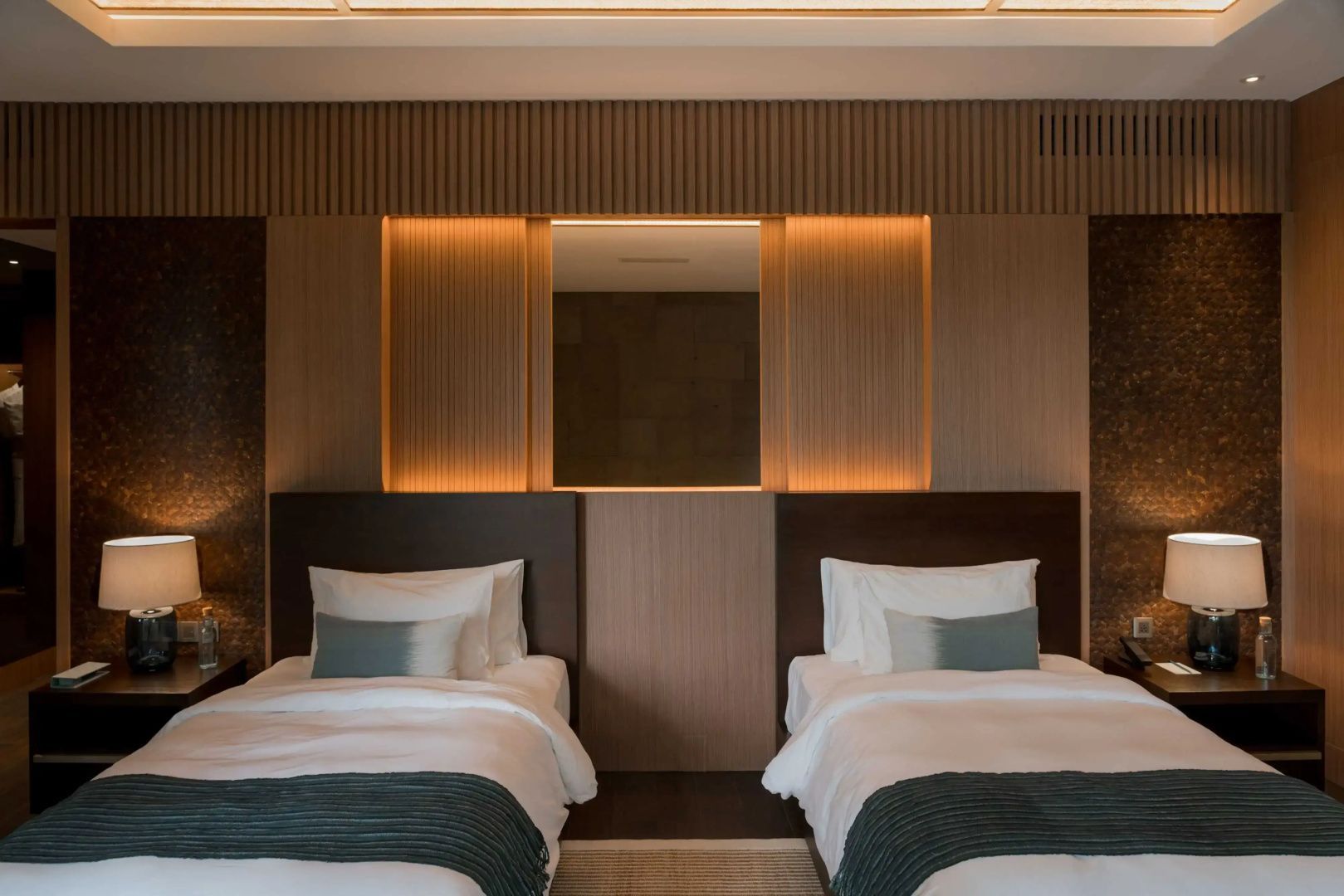 Schlafzimmer mit zwei Einzelbetten, weißer Bettwäsche und Holzverkleidung an der Wand.