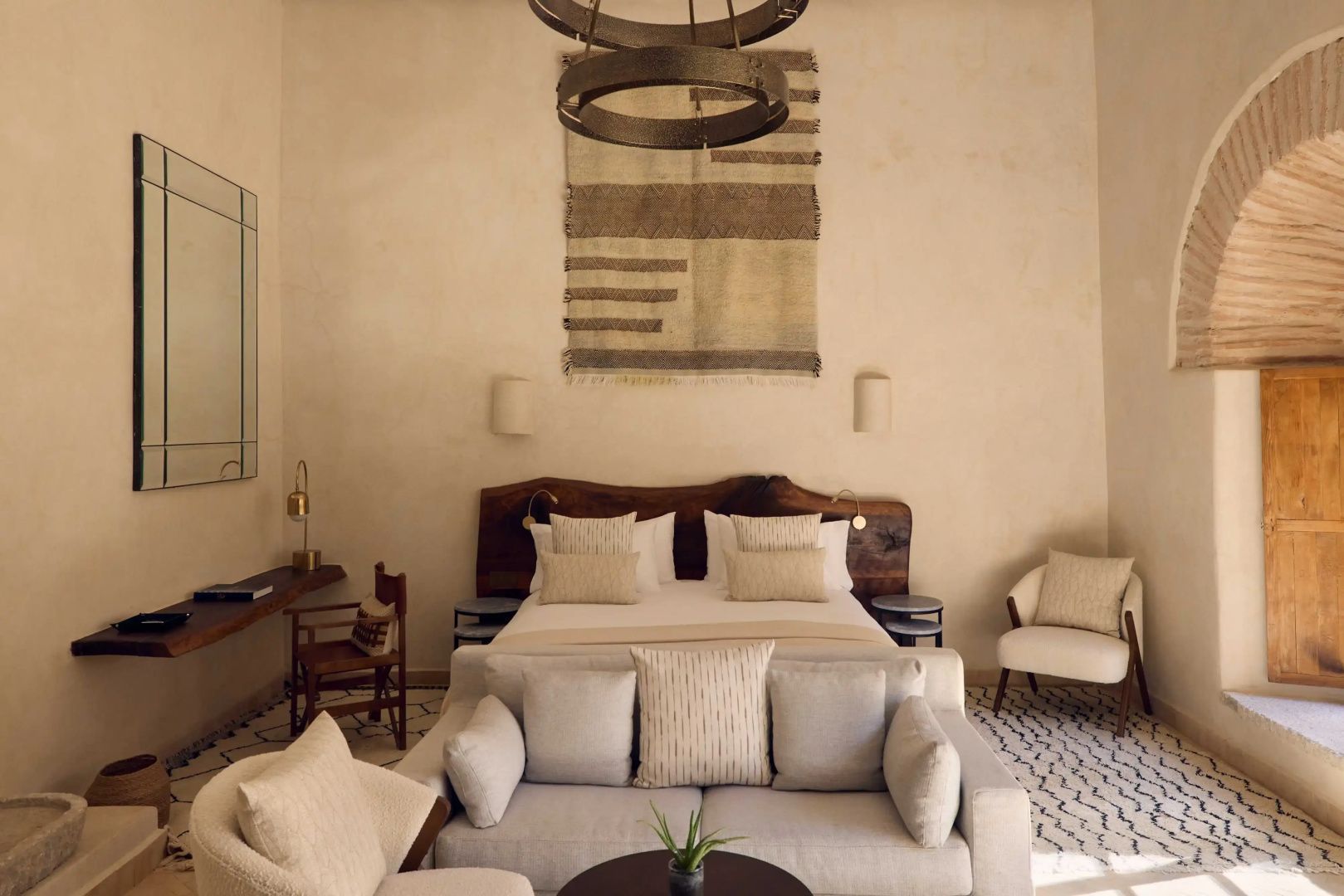 Schlafbereich in einer Suite mit Doppelbett, vorgelagertem Sofa und Wandteppich.