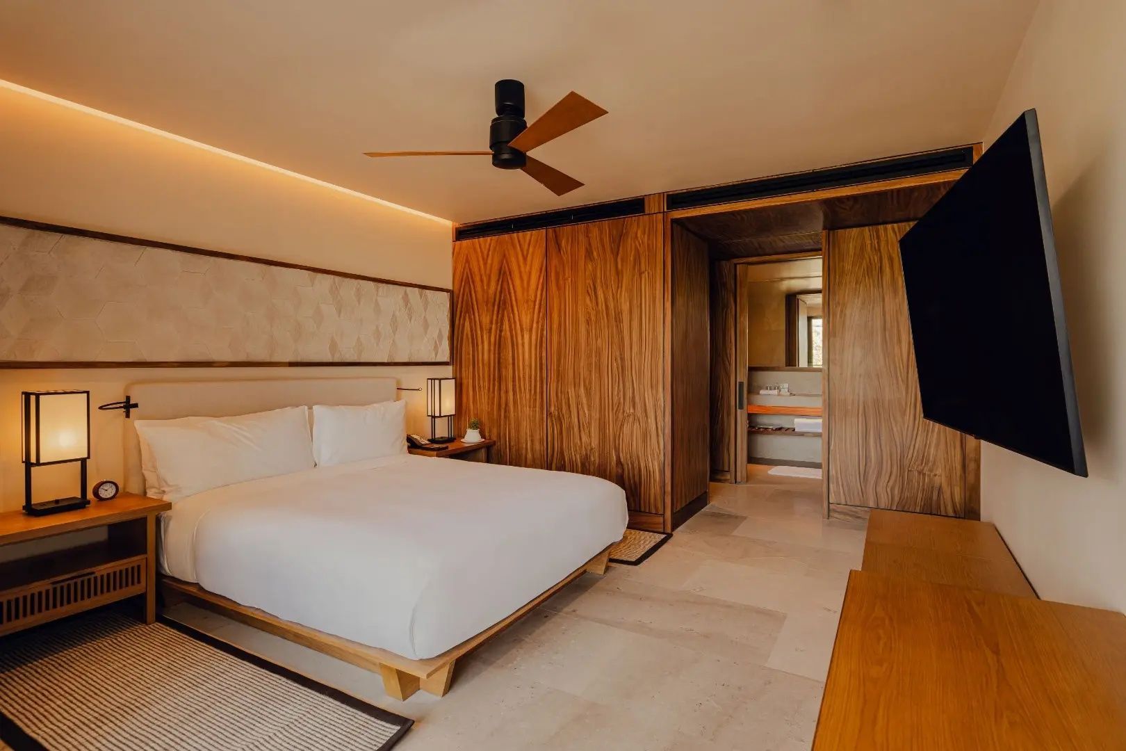 Schlafzimmer mit Doppelbett, Holzverkleidung, Ventilator und Durchgang zum Badezimmer.