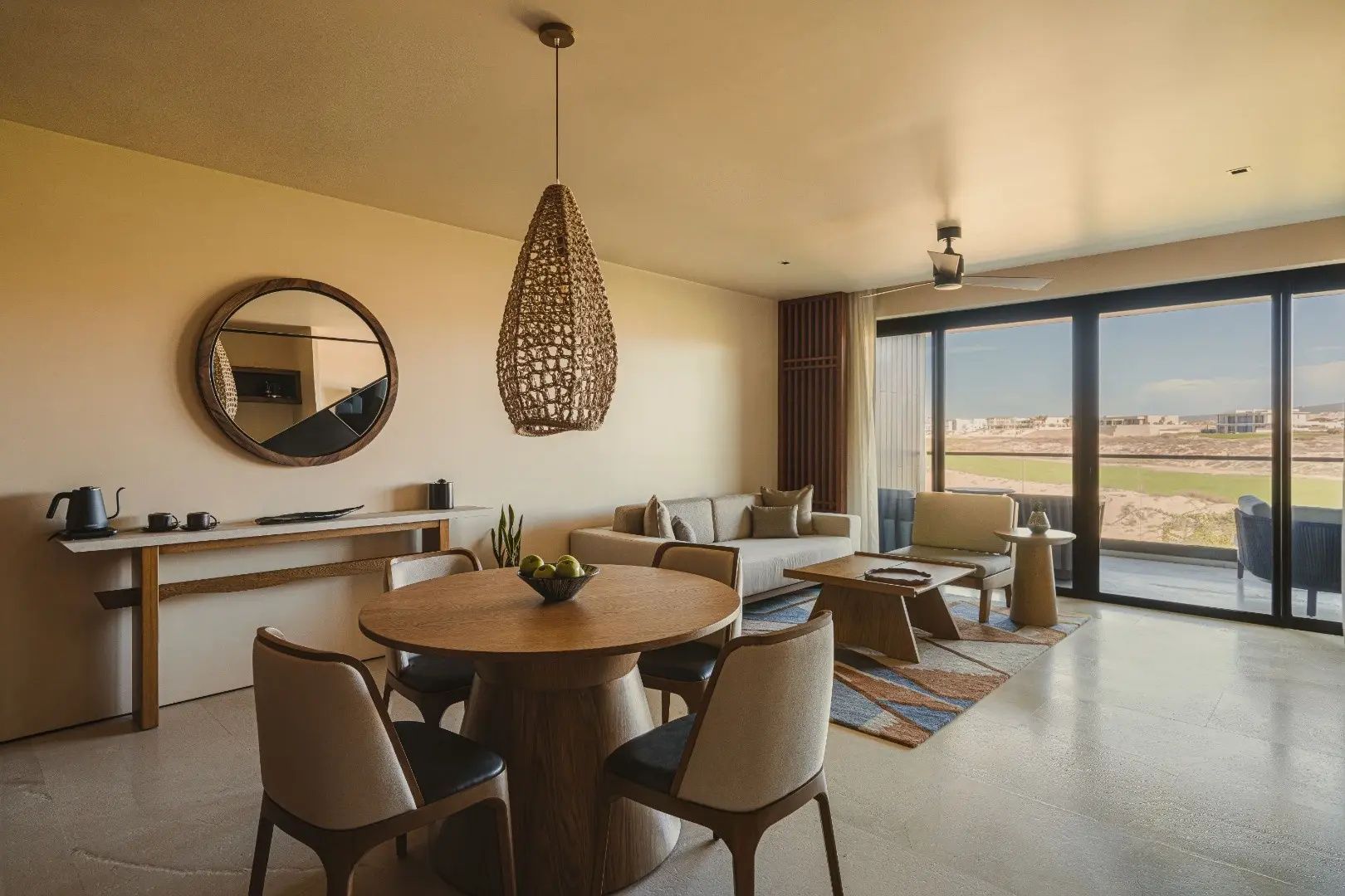 Wohn- und Essbereich einer Suite mit Sofa, Holzmöbeln und großer Fensterfront.