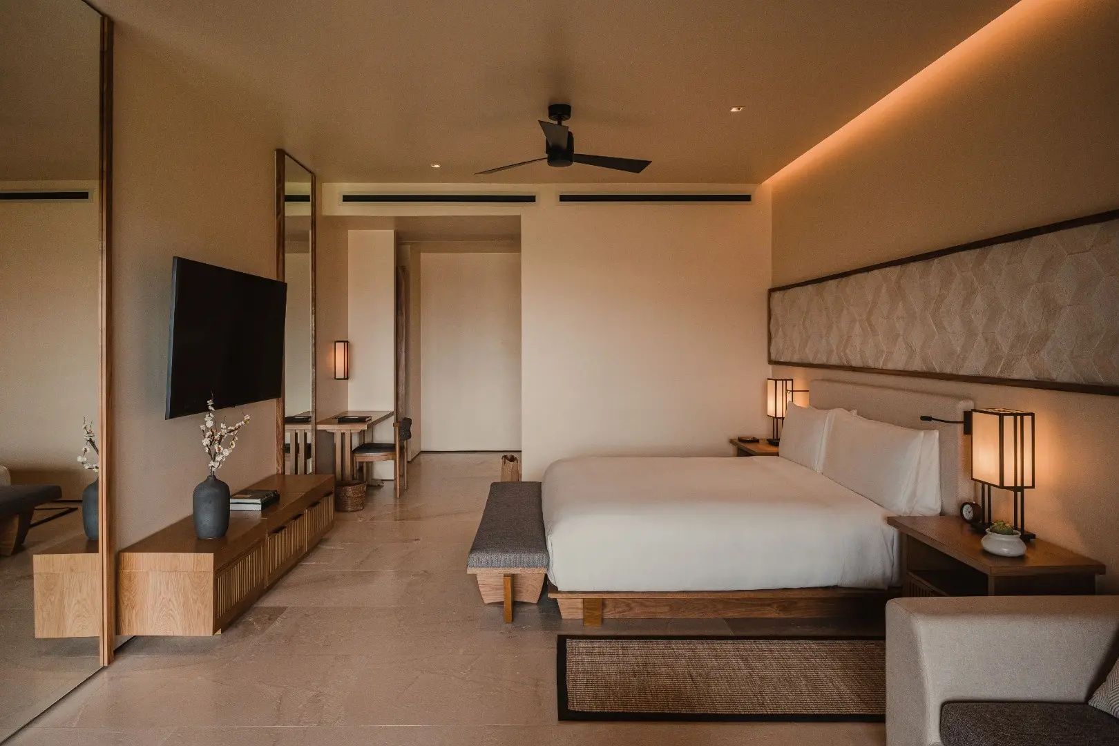 Modern eingerichtetes Hotelzimmer mit großem Doppelbett, Holzmöbeln und Fernseher