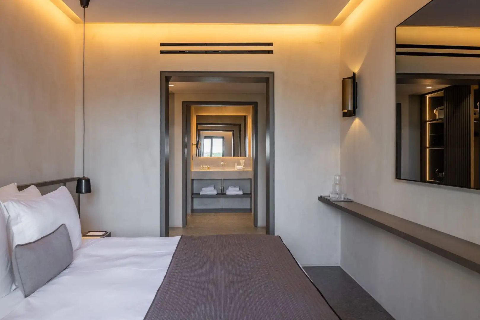 Blick vom Schlafzimmer durch einen Durchgang auf das Badezimmer mit Waschtisch.