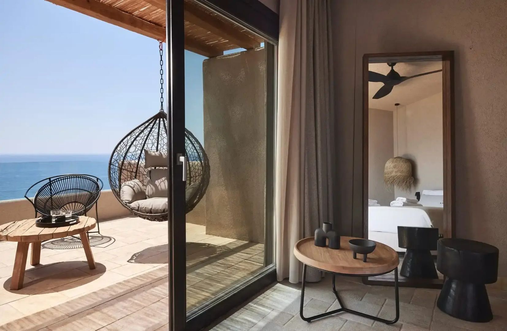 Balkon mit einem Hängesessel und Meerblick, fotografiert von innen.