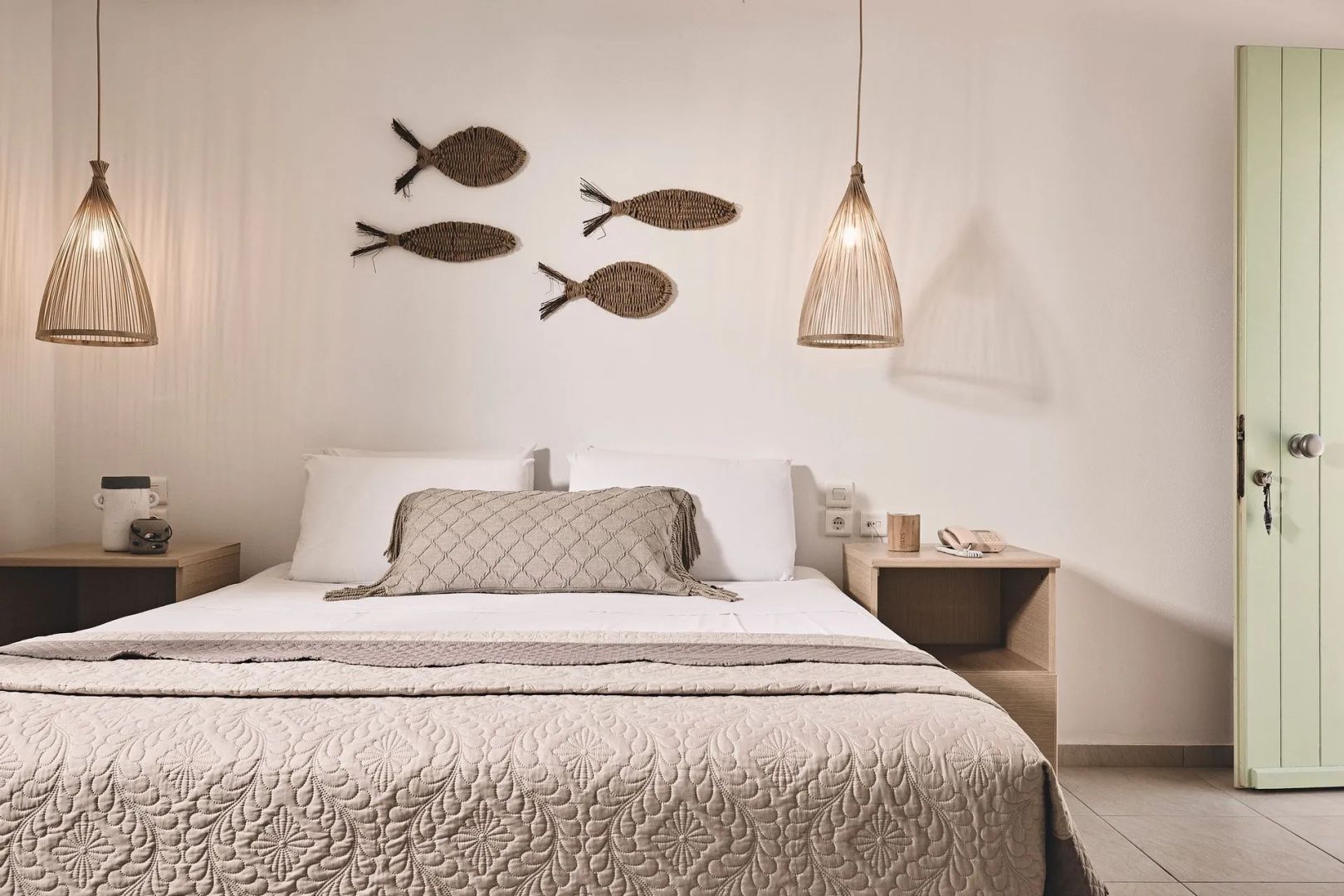 Doppelbett mit hellbrauner Tagesdecke, Fischdekoration an der Wand und Hängeleuchte.