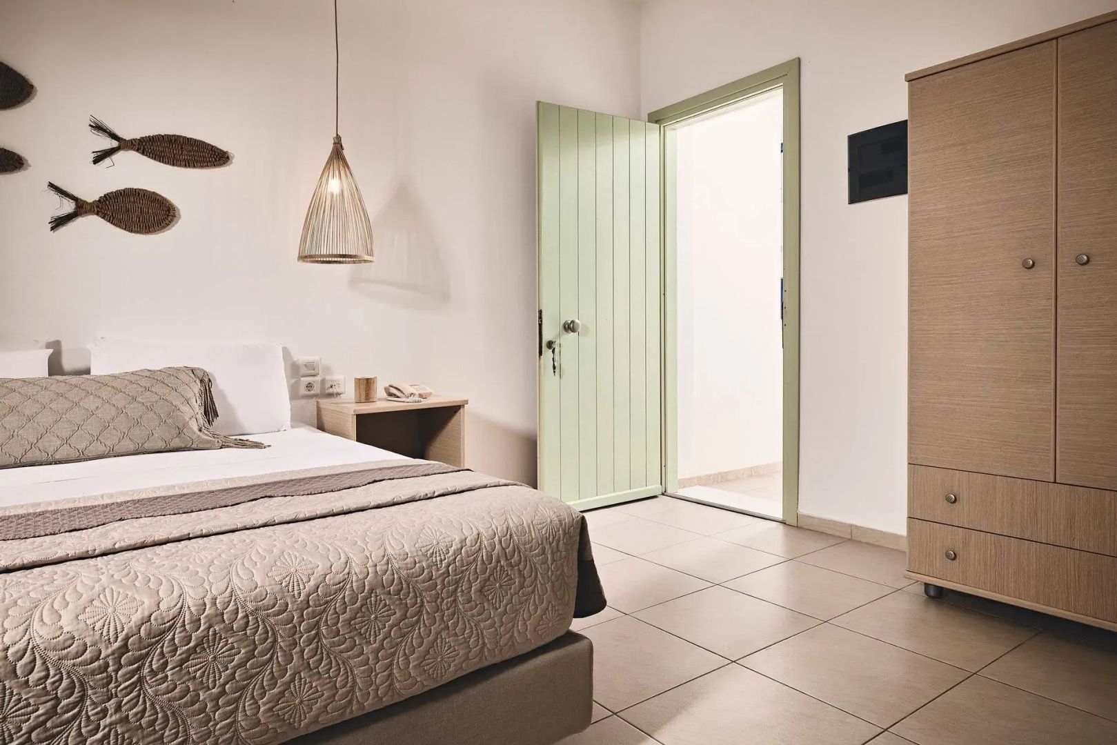 Blick durch das Schlafzimmer auf die geöffnete grüne Eingangstür und den Fliesenboden.
