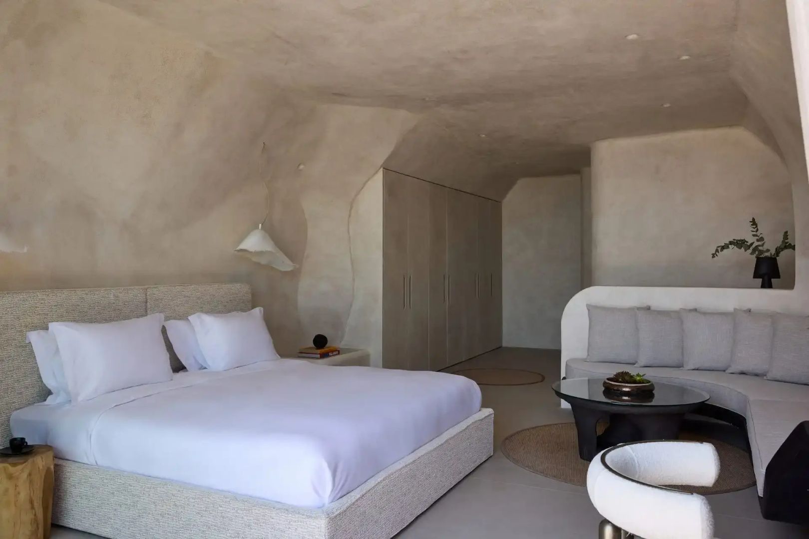 Modernes Hotelzimmer mit hellen Wänden, Doppelbett und kleiner Sitzecke.