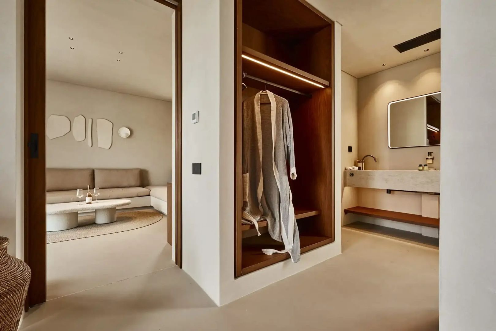 Offener Ankleide und Waschtischbereich in einer Suite mit Bademantel im offenen Regal
