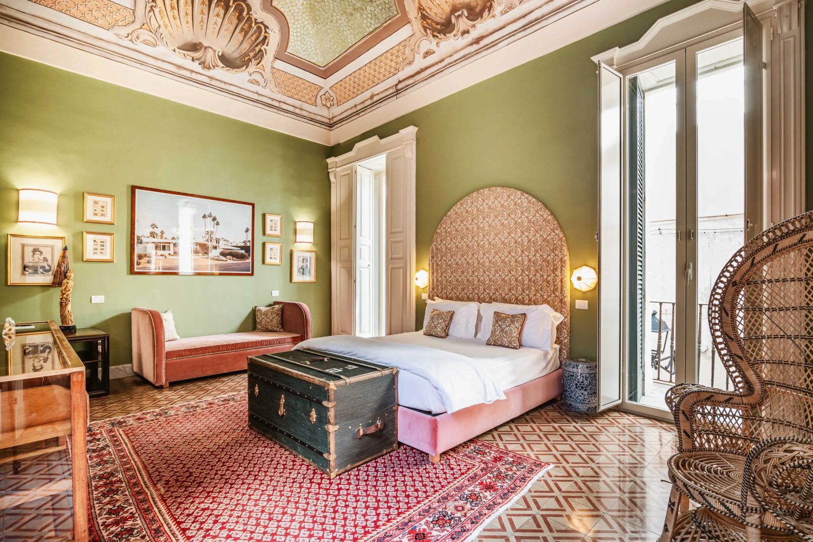 Großzügiges Zimmer mit verzierten Deckenfresken, Doppelbett, Truhe und grün gestrichenen Wänden.