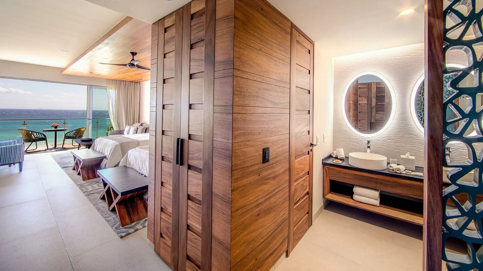 Großer Holzschrank als Raumtrenner zwischen Schlafbereich und Bad mit Waschtisch.