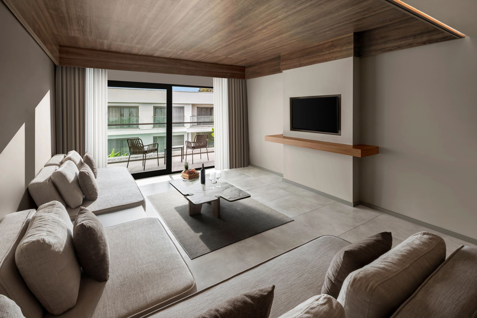 Moderner Wohnbereich mit großem Sofa, Wand-Fernseher und Zugang zum Balkon