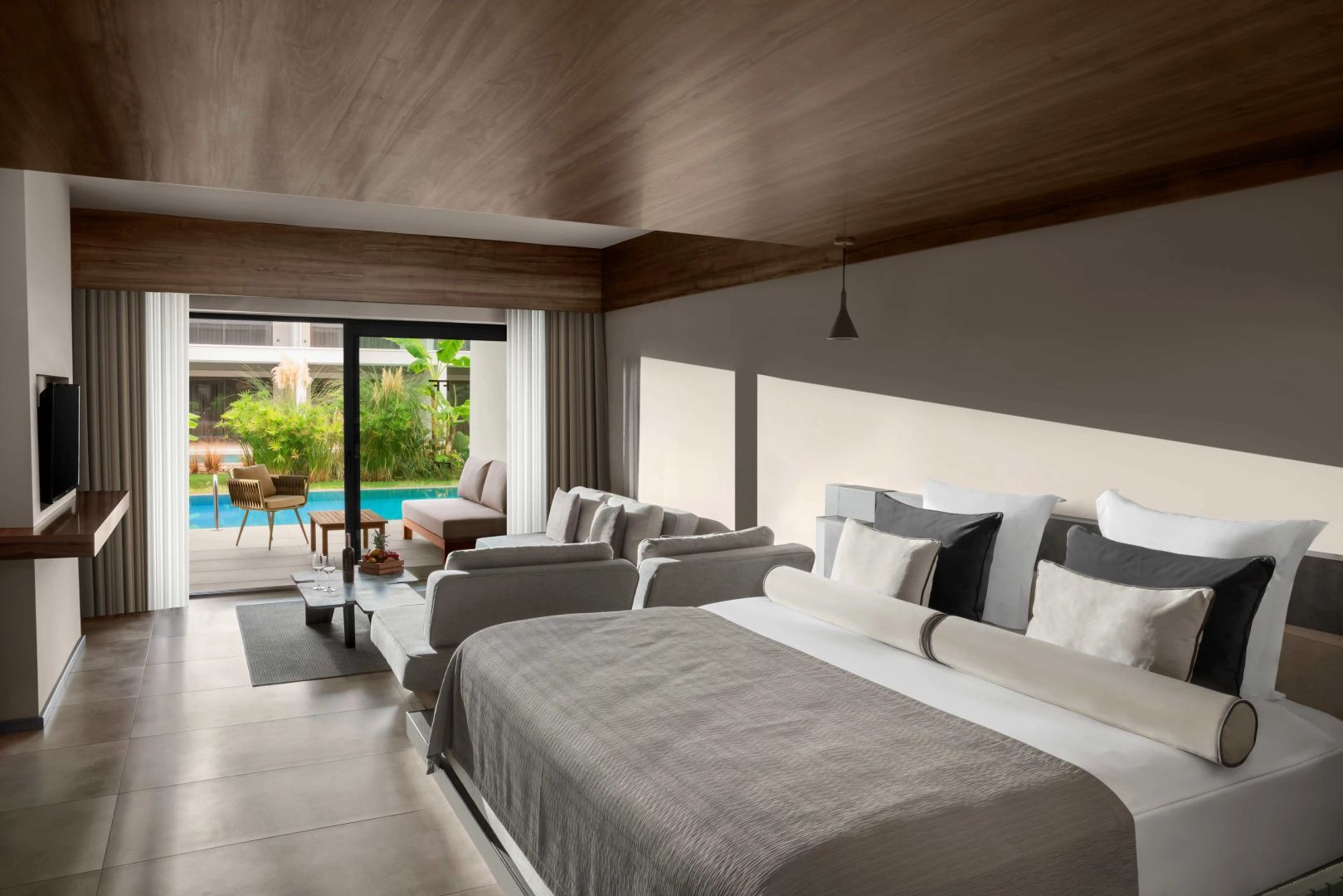 Geräumiges Hotelzimmer mit Doppelbett, Sitzbereich und Terrasse mit Poolblick