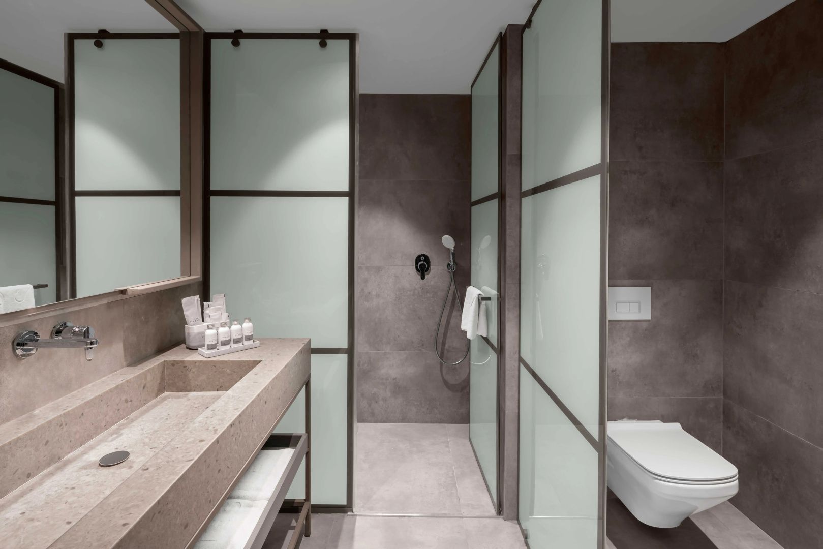 Modernes Badezimmer mit Waschtisch aus Stein, Dusche und getrennter Toilette.