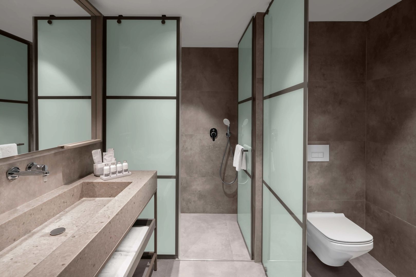 Badezimmer mit modernem Waschtisch aus Stein, Abtrennungen aus Mattglas und Dusche.