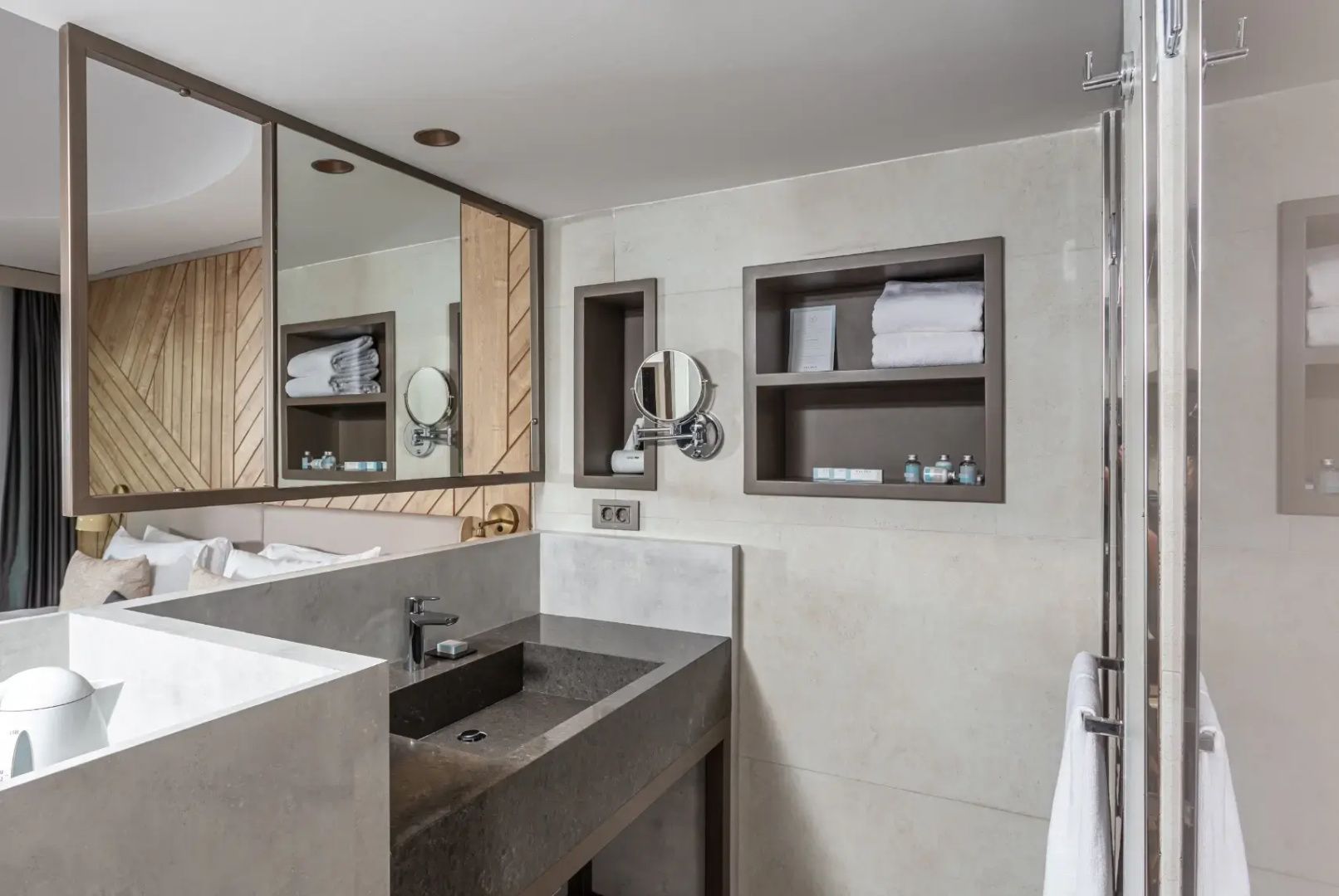 Badezimmer mit dunklem Steinwaschbecken, großem Spiegel und Regalen für Handtücher.