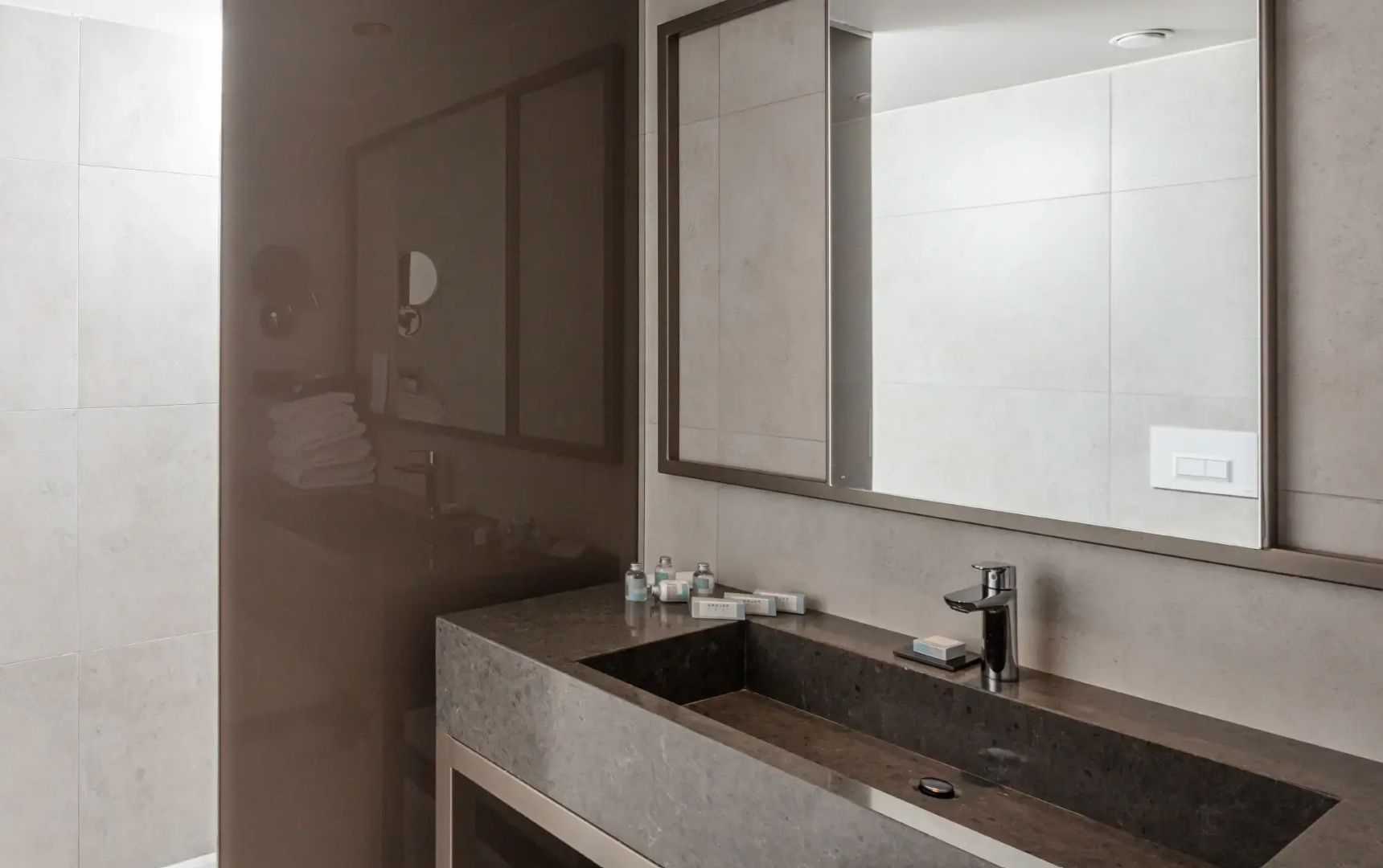 Waschtisch mit dunkelgrauem Waschbecken, Armatur und Spiegel im Badezimmer.