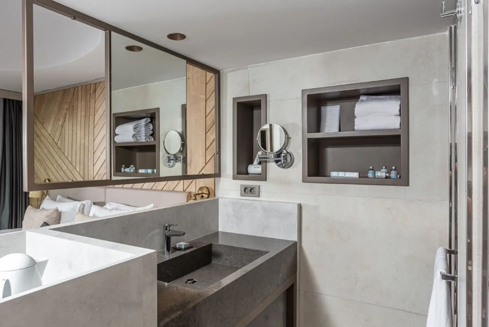 Waschbecken im Badezimmer mit Spiegel, Rasierspiegel und Handtüchern im Regal.