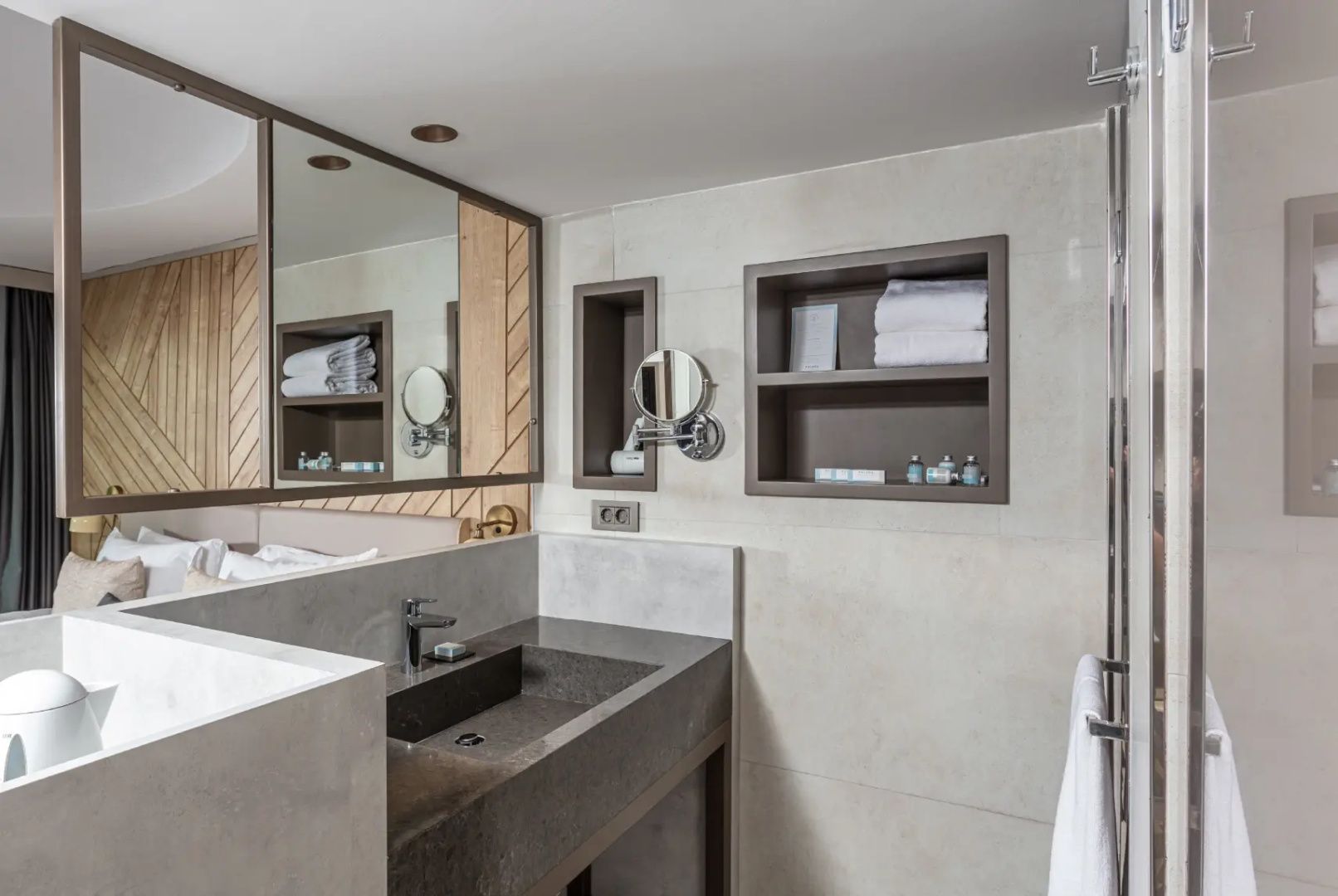 Modernes Badezimmer mit dunklem Waschtisch, Spiegel, Kosmetikspiegel und Wandregalen für Handtücher.