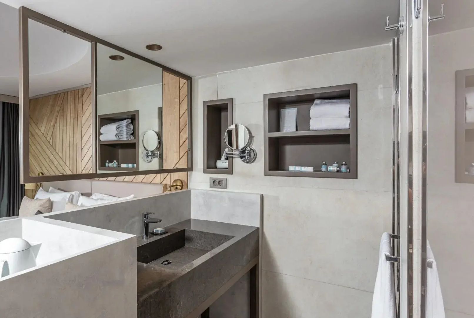 Badezimmer mit dunklem Steinwaschbecken, großem Spiegel und Handtuchablage.