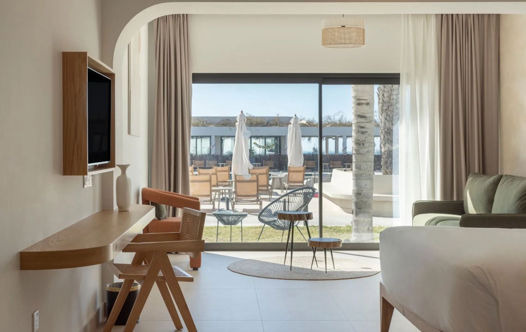 Blick aus dem Hotelzimmer auf die Terrasse und den Außenbereich mit Sonnenschirmen.