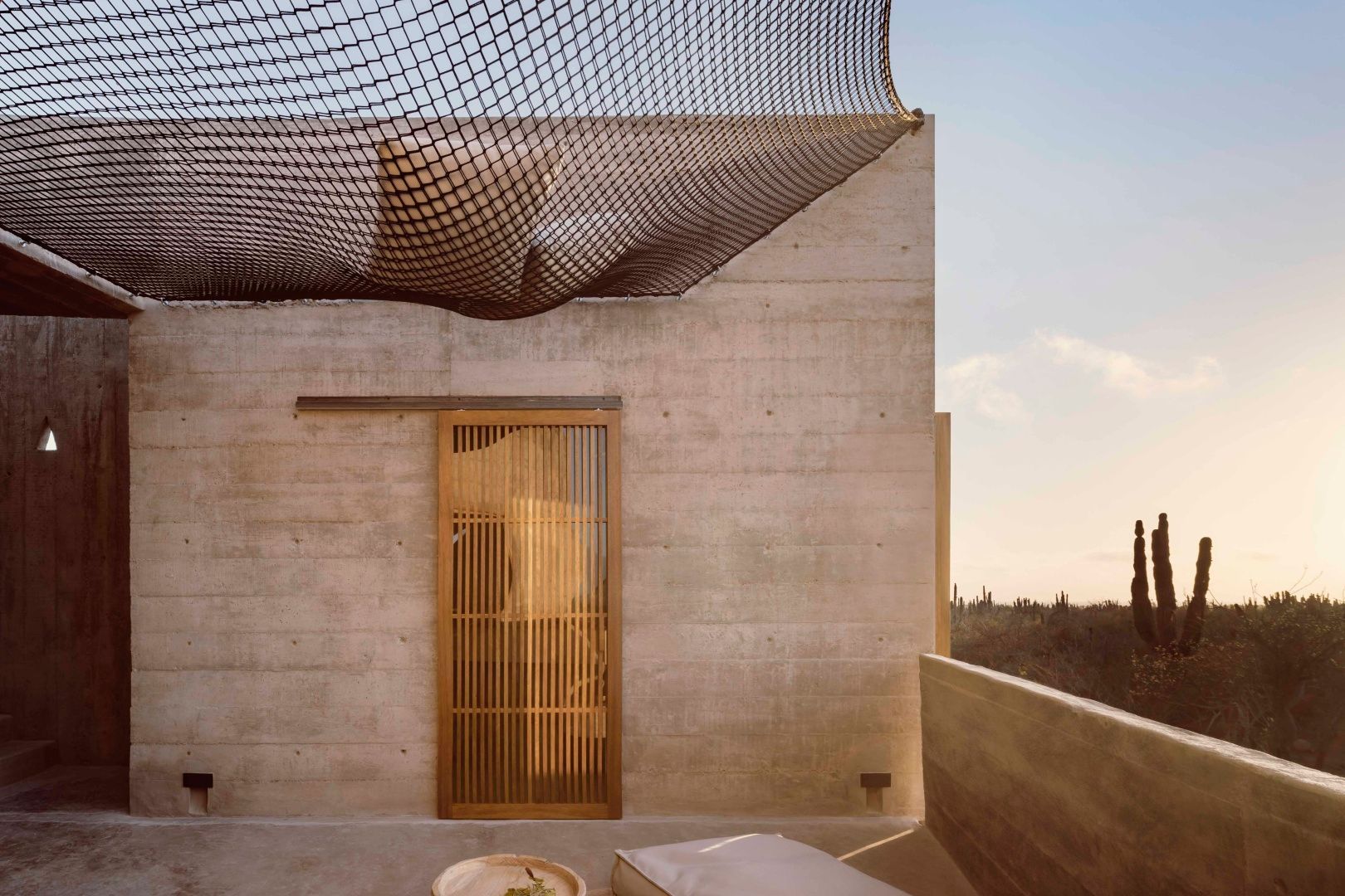 Dachterrasse aus Sichtbeton mit aufgespanntem Liegenetz und einer Holztür.
