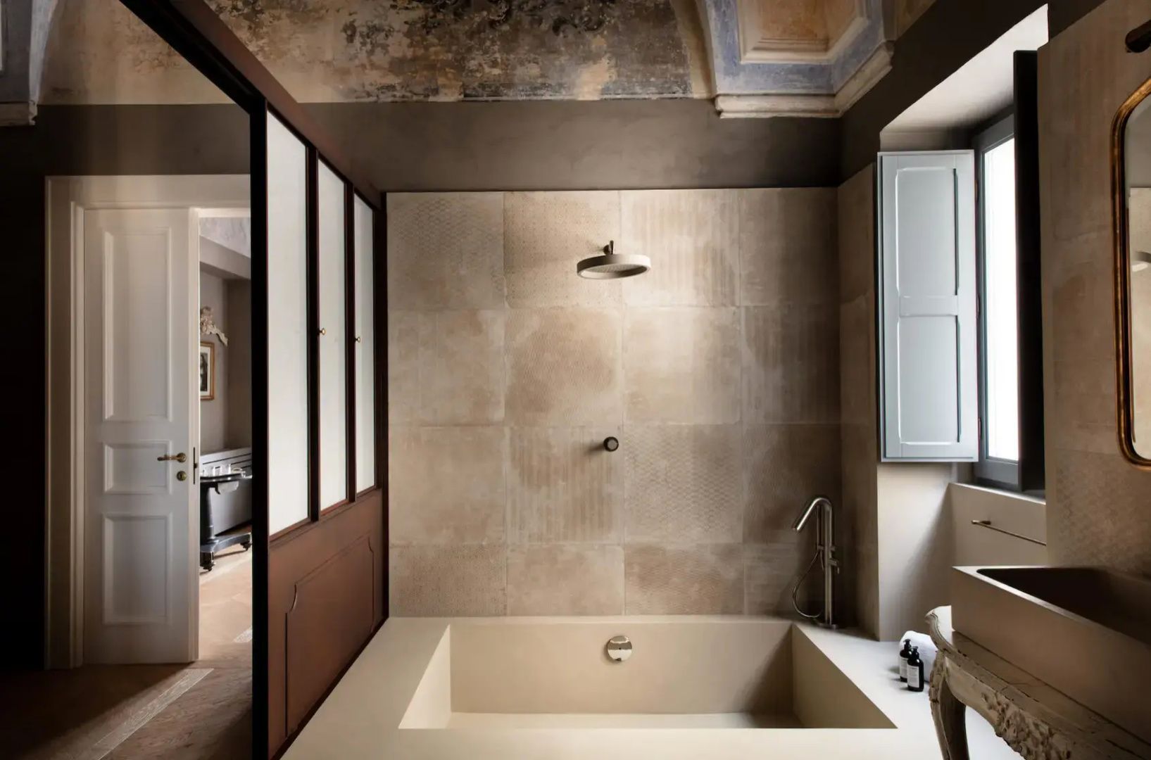 Geräumiges Badezimmer mit tief eingelassener Badewanne, Regendusche und beigen Fliesen.