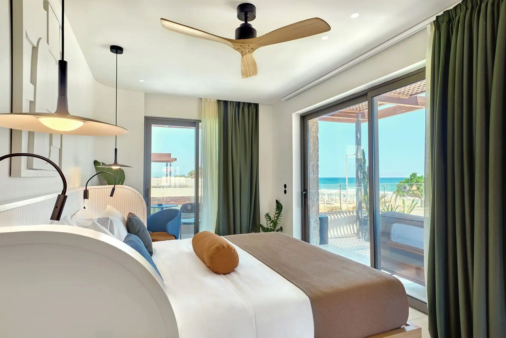 Hotelzimmer mit großer Glasfront und direktem Blick auf das Meer und den Strand.