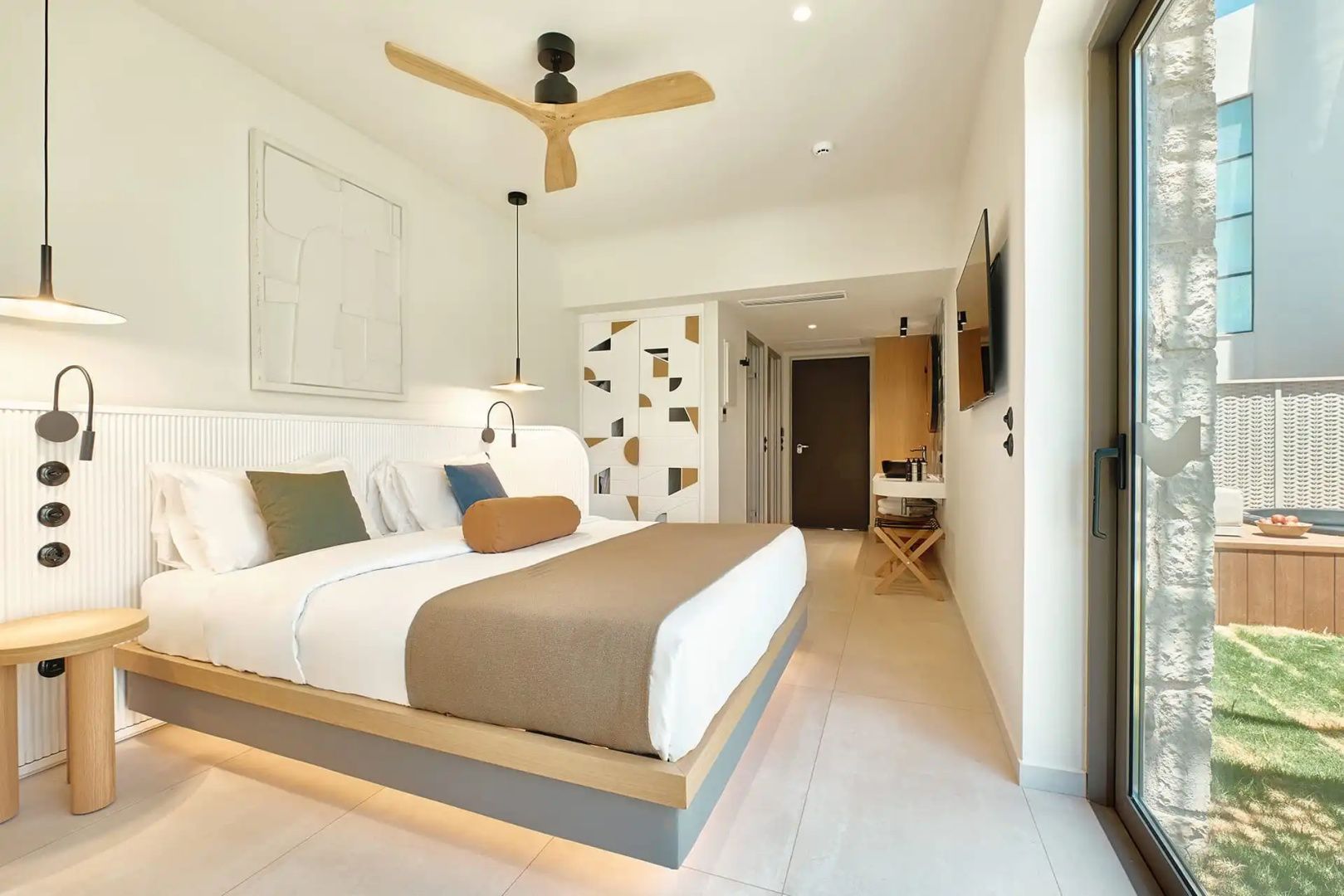 Doppelbett in einem hellen Hotelzimmer mit Holzdeckenventilator und moderner Wandgestaltung.