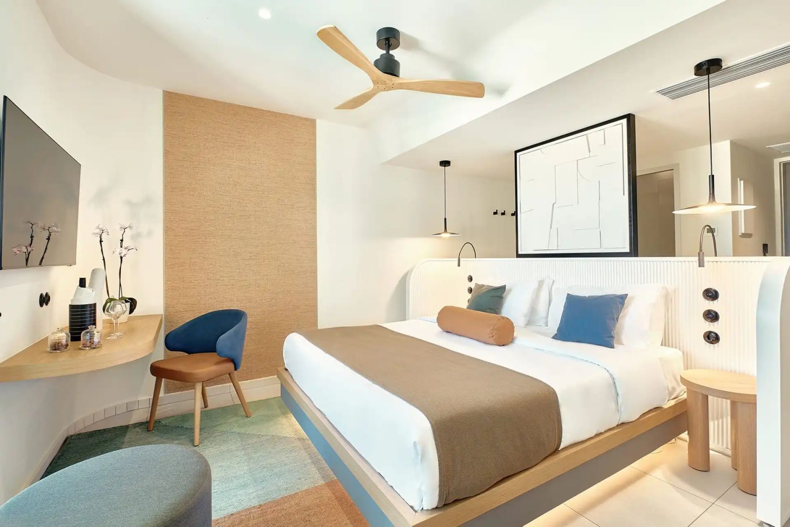 Modernes Hotelzimmer mit Doppelbett, Holzventilator und blauen Kissen.