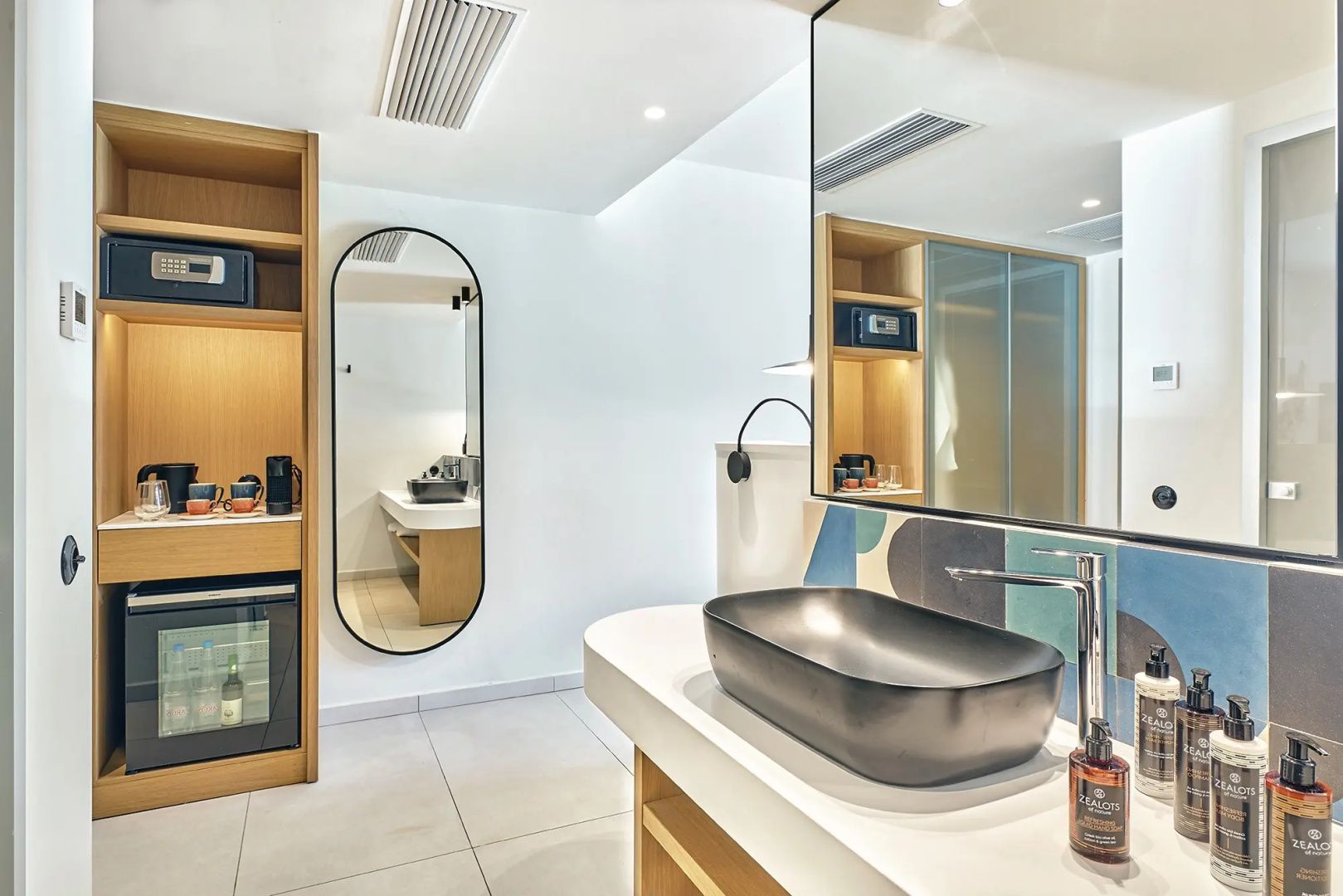 Waschbereich im Badezimmer mit modernem Aufsatzwaschbecken und großem ovalem Wandspiegel.