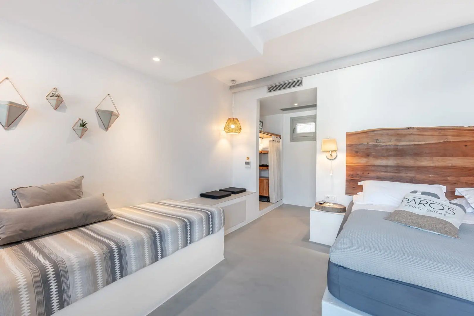 Hell gestaltetes Schlafzimmer mit Holzkopfteil, gepolsterter Liege und Durchgang.