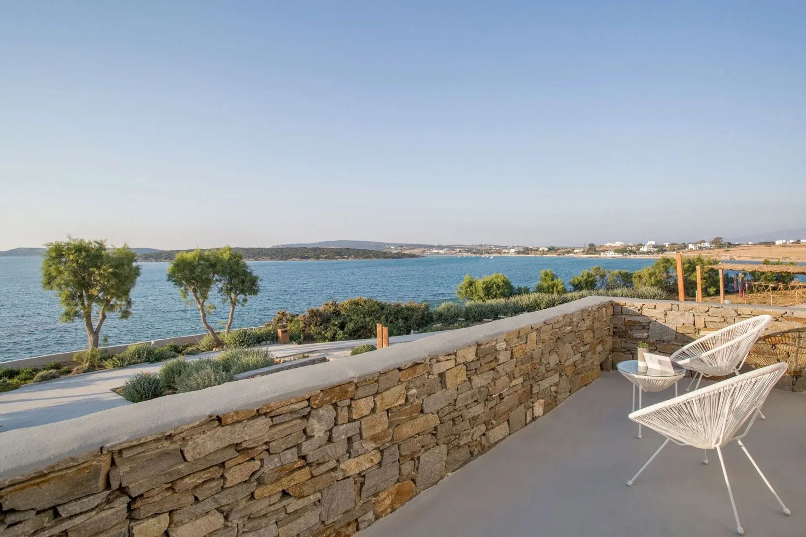 Terrasse mit einer Natursteinmauer und Blick auf das ruhige Meer und die Gegenküste.