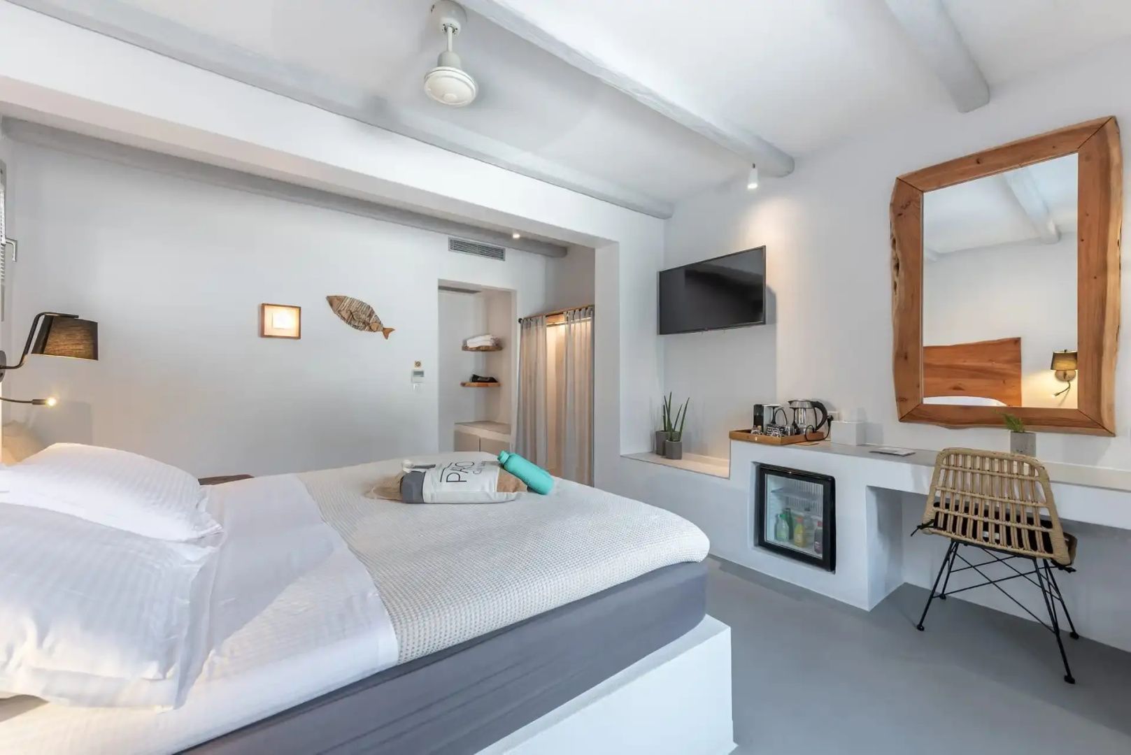 Hotelzimmer mit Minibar, Fernseher an der Wand und offenem Schrankbereich.