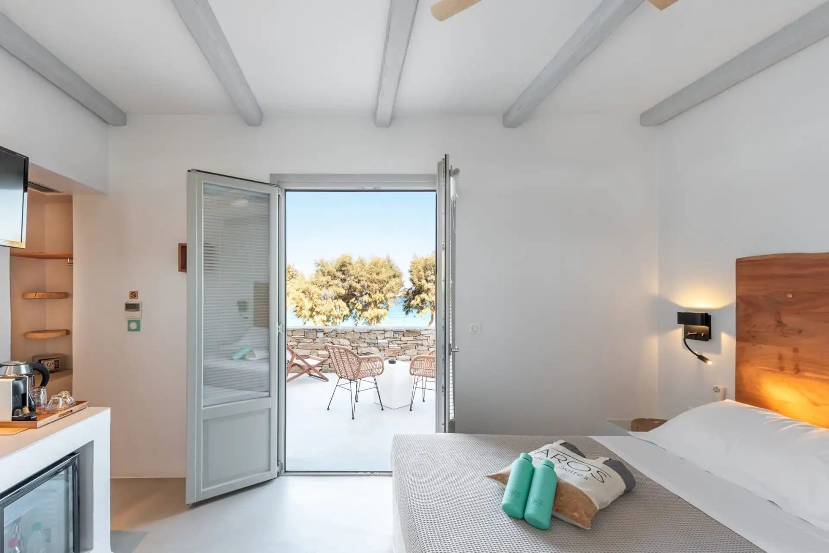 Blick aus einem hellen Schlafzimmer durch eine offene Tür auf die Terrasse und das Meer.