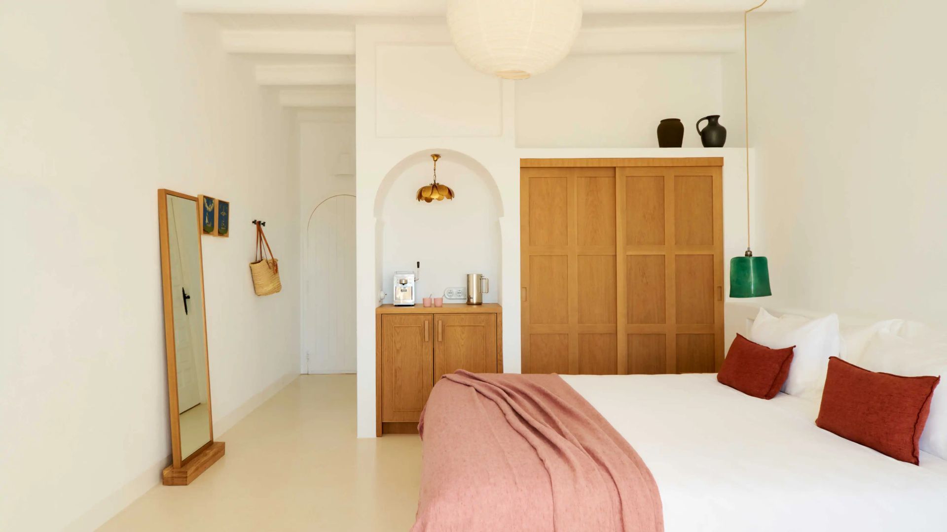 Helles Hotelzimmer mit Holzeinbauschränken, Kaffeestation in einer Nische und Bett.