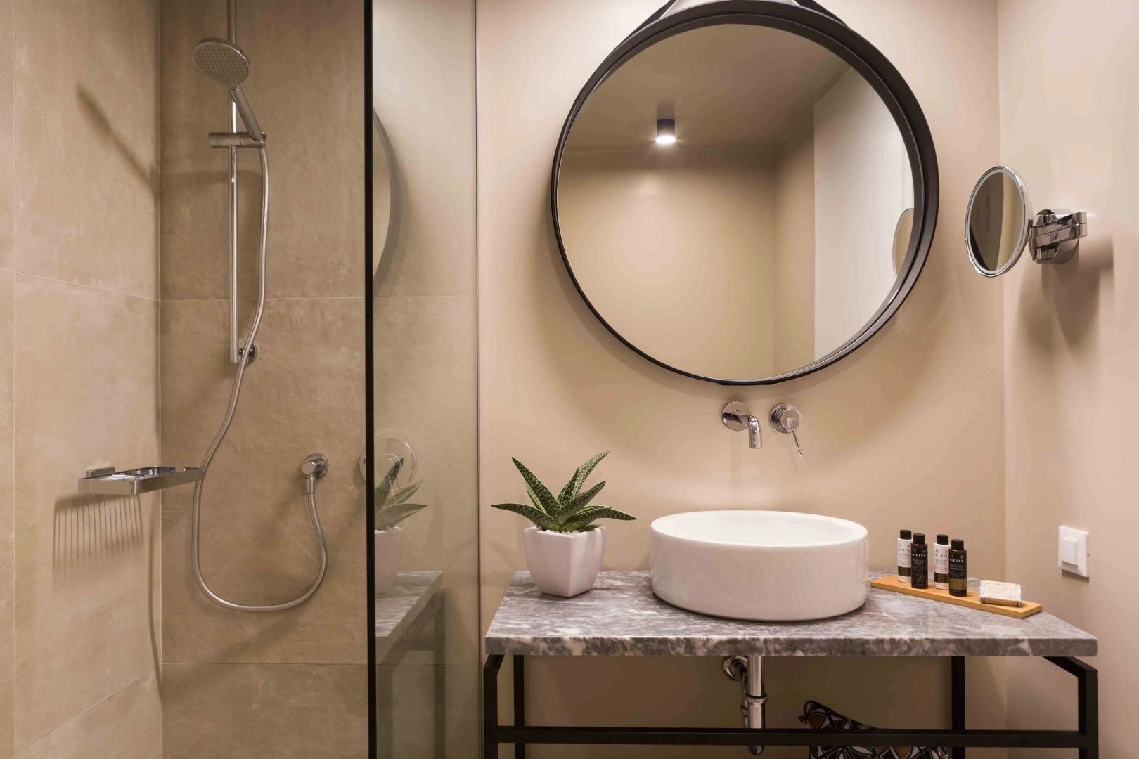Waschplatz im Badezimmer mit rundem Spiegel, Aufsatzwaschbecken und Dusche.