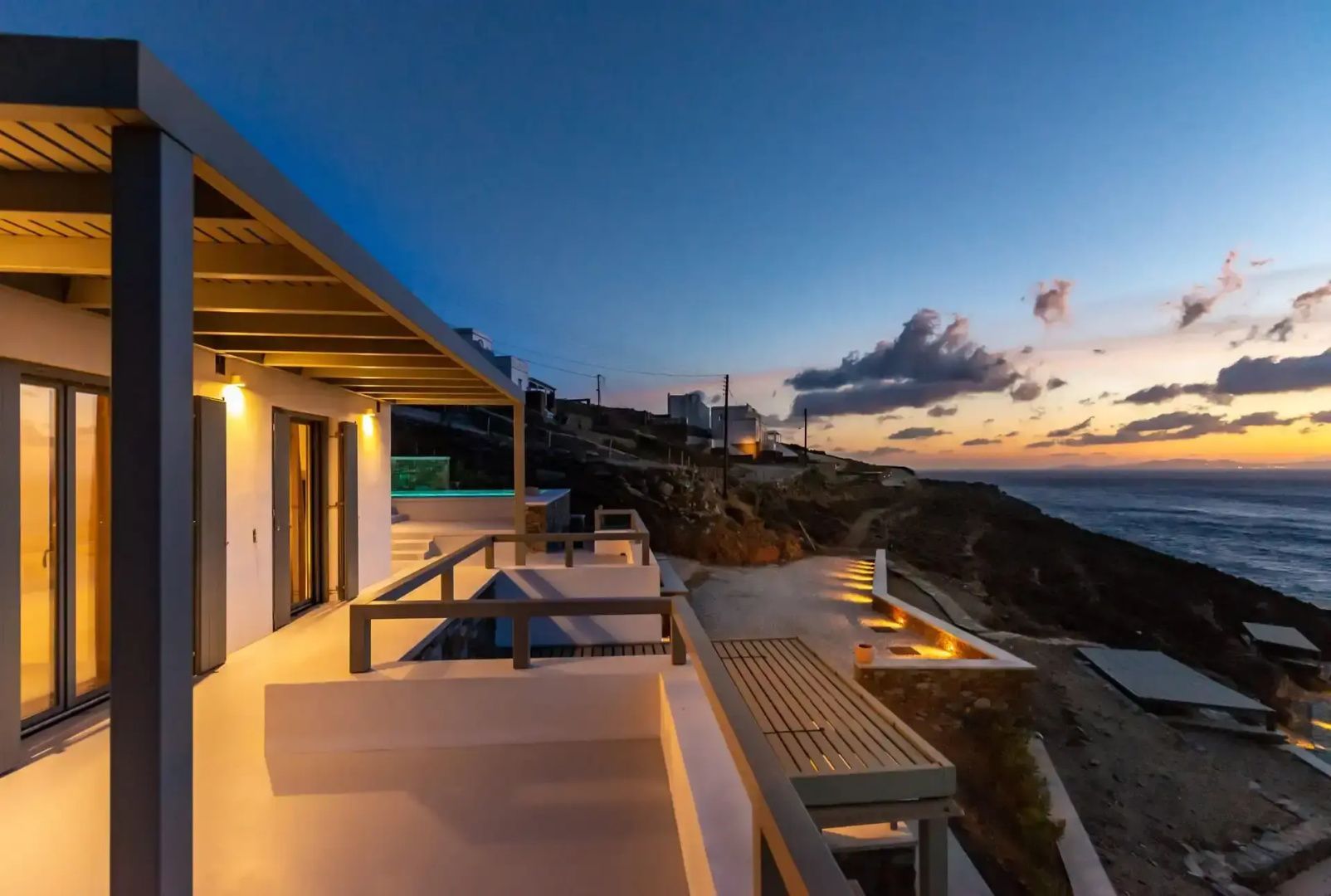 Moderne Terrasse einer Villa bei Dämmerung mit Blick auf die Küste und das Meer.