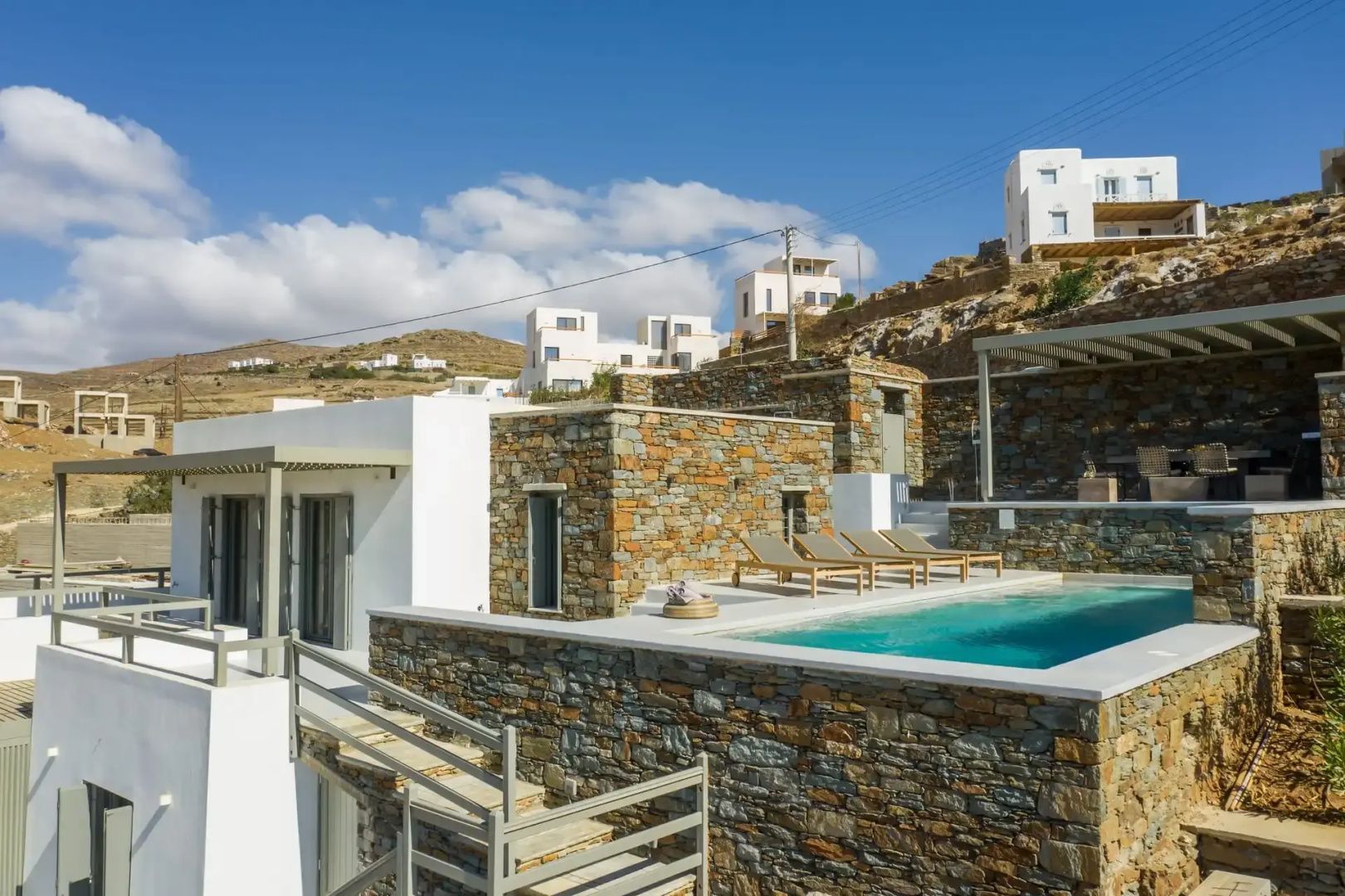 Natursteinvilla mit integriertem Pool, Sonnenliegen und traditioneller Architektur auf Tinos.