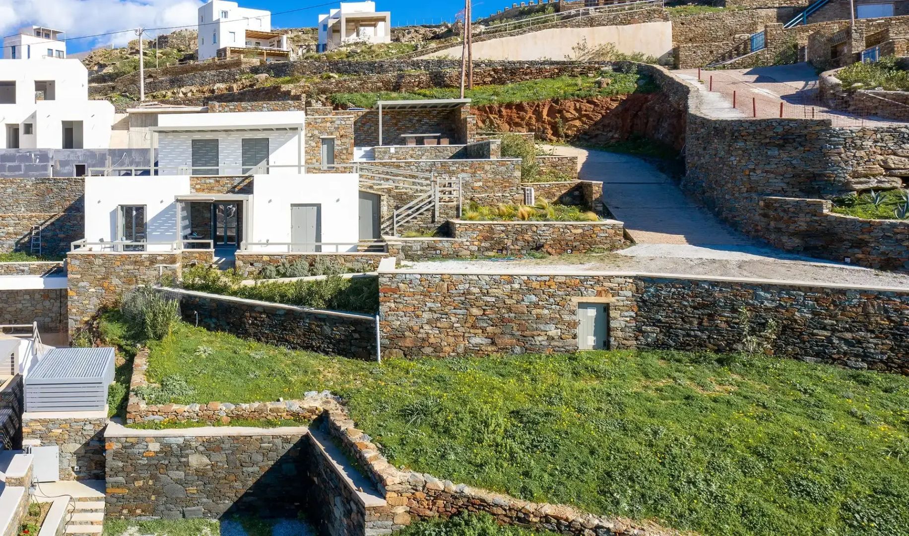 Moderne weiße Villen und Natursteinmauern an einem Hang auf Tinos.