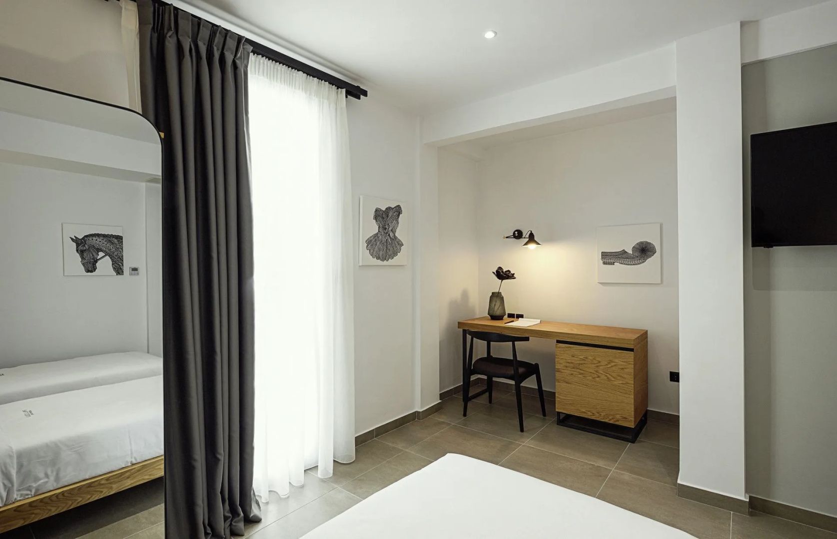 Arbeitsbereich im Hotelzimmer mit Holztisch, schwarzem Stuhl und Deko-Vase.