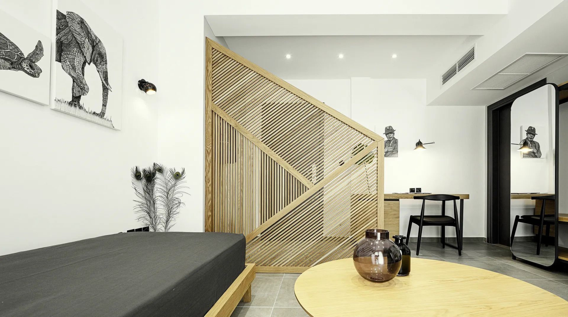 Sitzbereich im Hotelzimmer mit Holztisch, Liege und Holzraumteiler.