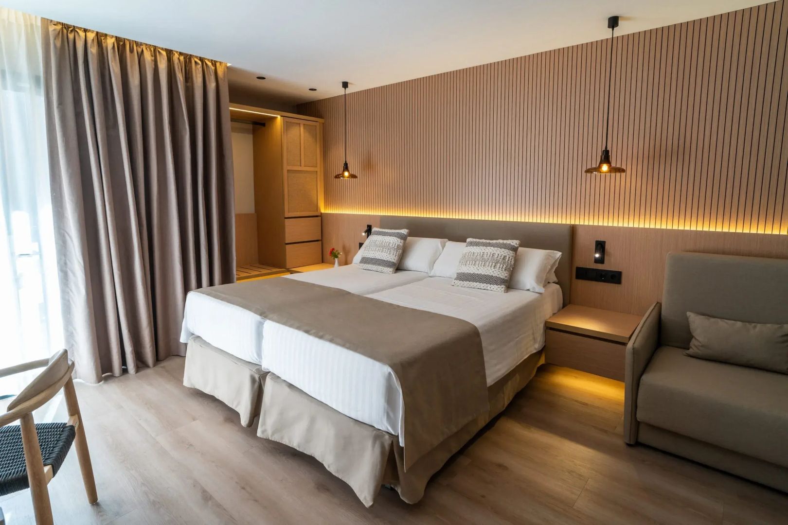 Doppelbett mit weißer Bettwäsche und Holzverkleidung samt integrierter Beleuchtung dahinter.